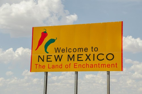 Welcome sign for New Mexico, featuring colorful chili peppers and the phrase "The Land of Enchantment."