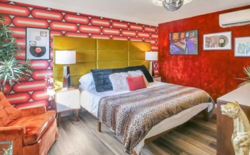 Colorful bedroom featuring a leopard print bedspread, vibrant red walls, and retro decor with a disco ball.