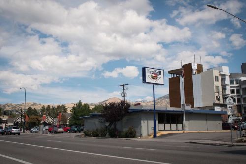 A street view of a Hires Big H restaurant with mountains and clouds in the background.