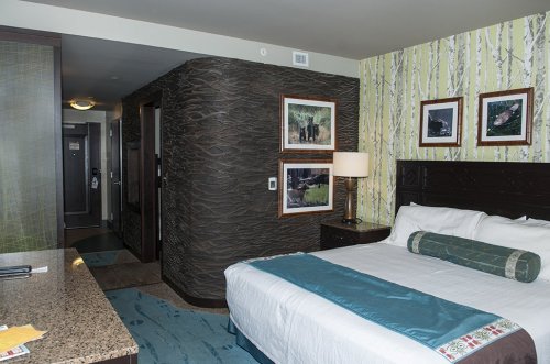 A cozy hotel room featuring a bed, decorative wall art, and a modern design with natural elements.