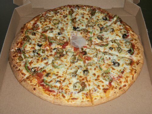 A large pizza with cheese, green peppers, olives, and a pizza saver in a cardboard box.
