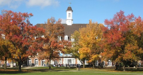 A historic building surrounded by vibrant autumn trees with colorful leaves under a clear blue sky.