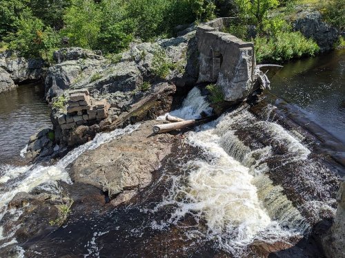A scenic view of a waterfall cascading over rocks, with lush greenery surrounding the area.