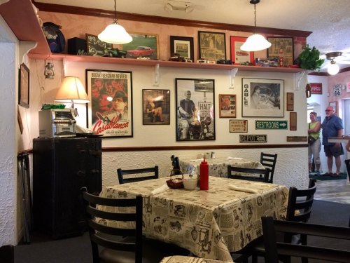 A cozy diner interior with vintage decor, a table set for dining, and a restroom sign in the background.