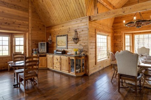 Cozy wooden dining area with large windows, a sideboard, and rustic furniture, featuring warm, natural lighting.