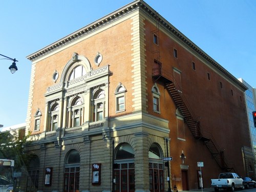 Historic brick building with ornate architectural details and a fire escape, set against a clear blue sky.