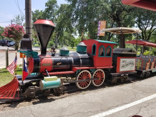 A colorful vintage train engine parked on a street, featuring flags and decorative details.