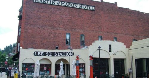 Historic building featuring the Martin & Mason Hotel sign and Lee St. Station, with outdoor seating and umbrellas.