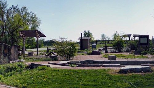A serene outdoor park featuring pathways, greenery, and various structures for relaxation and recreation.