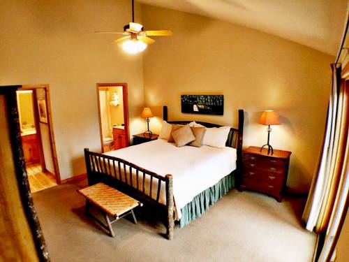 Cozy bedroom with a large bed, wooden furniture, lamps, and a warm color palette. Natural light from windows.