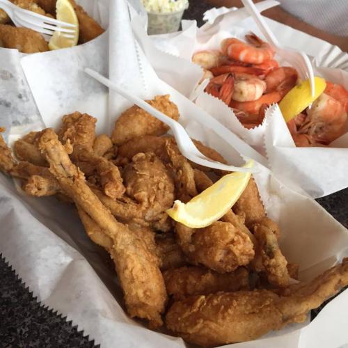 A platter of crispy fried chicken pieces with lemon wedges, alongside a serving of shrimp in a separate container.