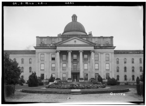Historic building with a large dome, columns, and landscaped grounds, captured in black and white.