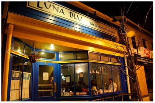 A cozy Italian restaurant, Luna Blu, illuminated at night with warm lights and a welcoming atmosphere.