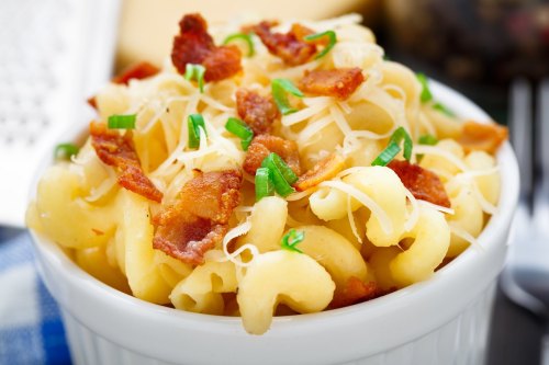 A bowl of creamy macaroni topped with crispy bacon and green onions.