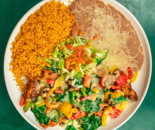 A plate of colorful Mexican food featuring grilled chicken, sautéed vegetables, rice, refried beans, and fresh salad.