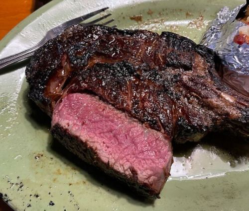 A perfectly cooked steak with a charred exterior and a juicy pink interior, served on a green plate.