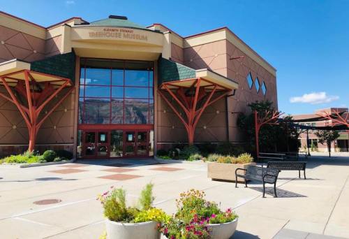 Exterior view of a modern museum building with large windows, colorful architecture, and landscaped planters.