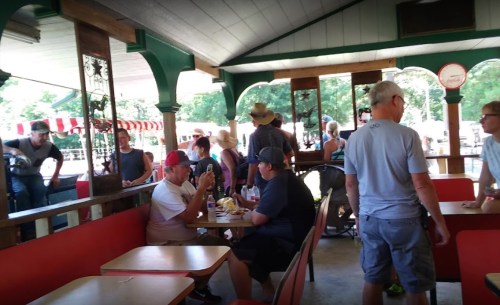 A busy indoor dining area with people eating, chatting, and standing at tables in a casual setting.