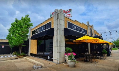 Exterior of Cheever's restaurant featuring outdoor seating, yellow umbrellas, and a cloudy sky.