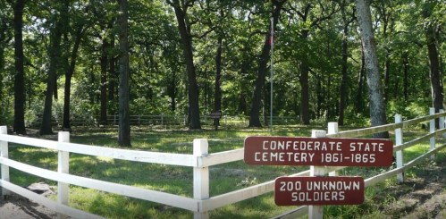 A peaceful cemetery with a white fence, marked by signs for Confederate State Cemetery and 200 unknown soldiers.