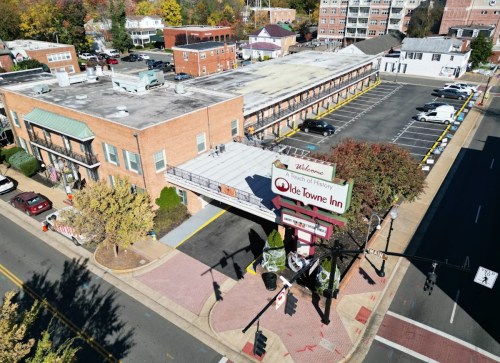 Aerial view of Olde Towne Inn with parking lot, surrounded by trees and buildings in a vibrant neighborhood.