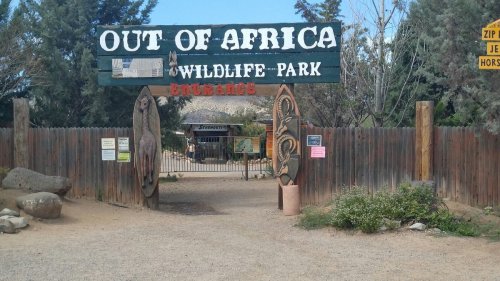 Entrance to Out of Africa Wildlife Park, featuring a large sign and decorative wooden carvings.