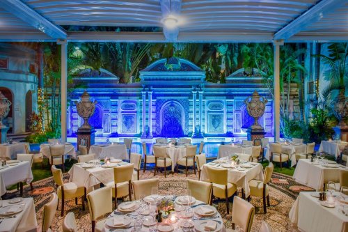 Elegant restaurant interior with white tables, surrounded by lush greenery and a beautifully lit decorative backdrop.