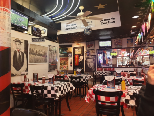A cozy diner with checkered tablecloths, vintage posters, and TVs, featuring a nostalgic, retro atmosphere.