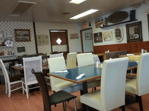 A cozy restaurant interior with a mix of chairs and tables, decorated walls, and a warm, inviting atmosphere.