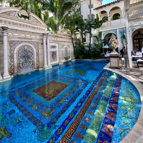 A luxurious pool surrounded by ornate tile work and lush greenery, featuring intricate designs and a serene atmosphere.