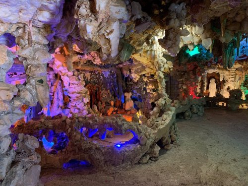 A colorful, cave-like interior with rock formations and illuminated areas, creating a mystical atmosphere.