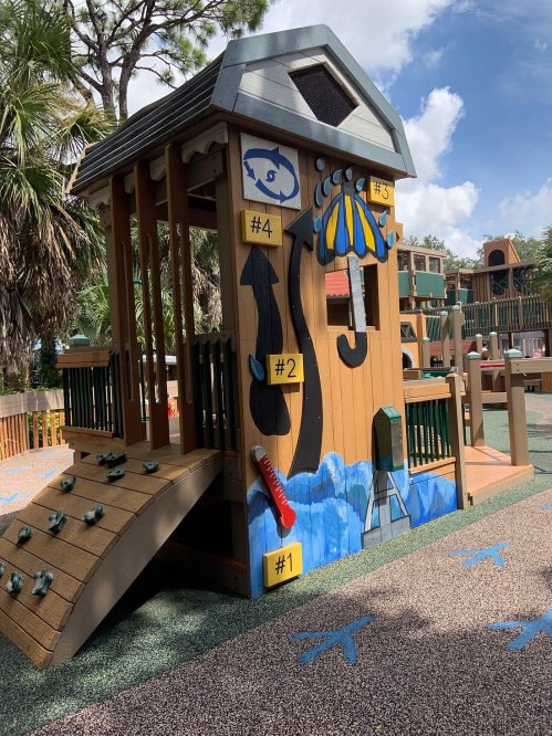 Colorful playground structure with climbing features, slides, and playful designs under a blue sky.