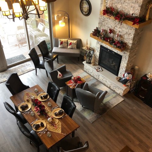 Cozy dining area with a wooden table set for a meal, a stone fireplace, and a warm, inviting atmosphere.
