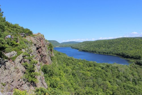 A scenic view of a river winding through lush green hills under a clear blue sky.