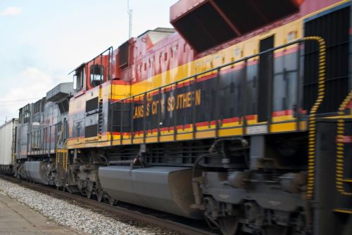 A colorful freight train in motion, featuring bold yellow and red designs on the locomotive.
