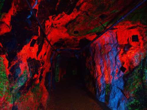 A dimly lit cave with vibrant red and blue lighting illuminating the rocky walls.