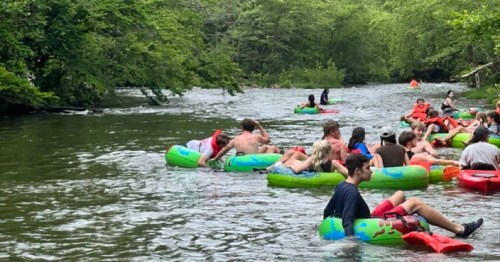 A group of people floating on colorful inner tubes in a river surrounded by lush greenery.