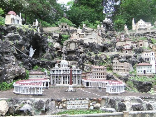 A miniature landscape featuring detailed replicas of famous buildings and structures, set among rocks and greenery.