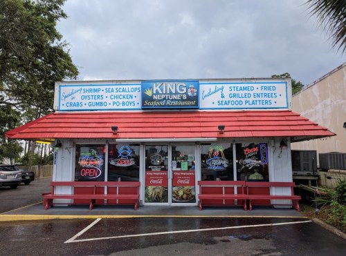 A seafood restaurant with a red roof, featuring a sign for "King Neptune's Seafood Restaurant" and an open sign.
