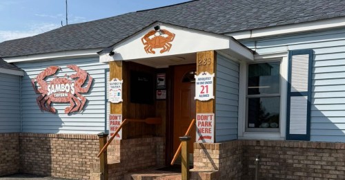 Exterior of crab shack in Delaware with orange crab out front under a blue sky