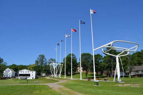 A clear blue sky above a grassy area with tall flagpoles and a large football goalpost structure.