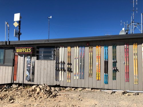 A building exterior with a sign reading "Waffles" and various colorful skis displayed on the wall.