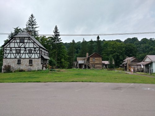 A scenic view of several rustic buildings surrounded by greenery under a cloudy sky.