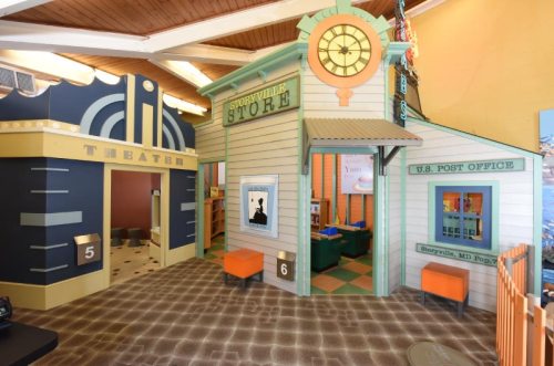 A colorful play area featuring a theater and a store with a post office, designed for children's imaginative play.