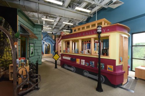 Colorful children's library featuring a train-themed reading area with books and playful decor.