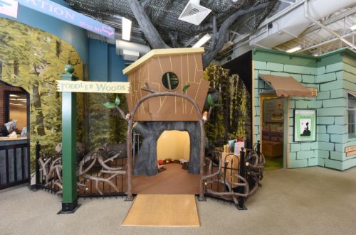 A whimsical play area featuring a treehouse entrance surrounded by branches and forest-themed decor.