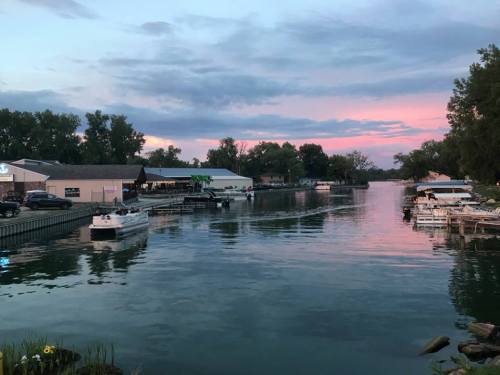 A serene river scene at dusk, with boats docked and colorful clouds reflecting on the water.