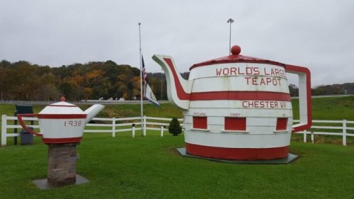 A large red and white teapot sculpture labeled "World's Largest Teapot" next to a smaller teapot, set in a grassy area.