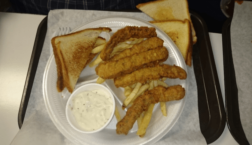 A plate with fried fish strips, French fries, toast, and a side of dipping sauce.
