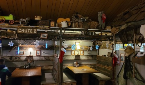 Cozy rustic restaurant interior with wooden decor, festive stockings, and vintage items on display.